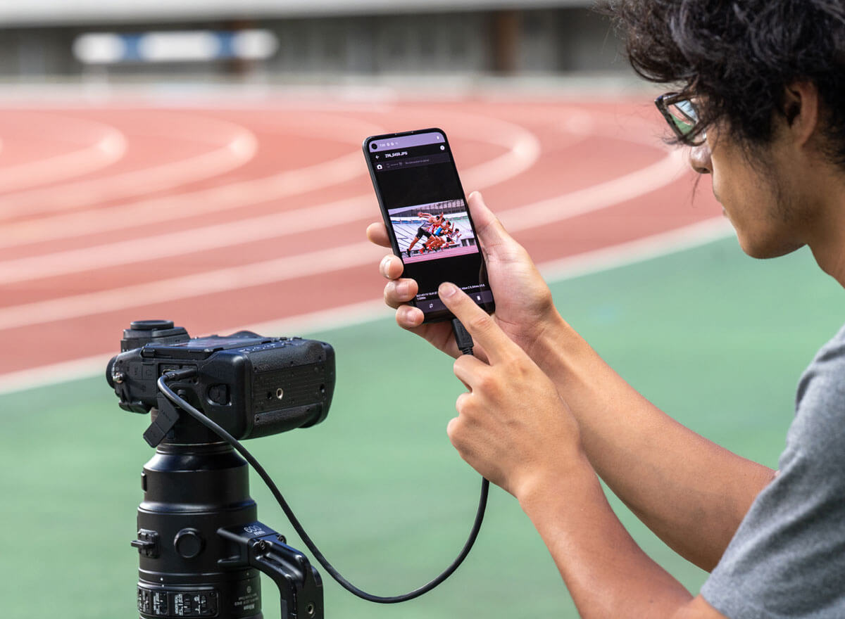 Photo of a photographer using a smartphone connected to the Z 9, highlighting NX MobileAir